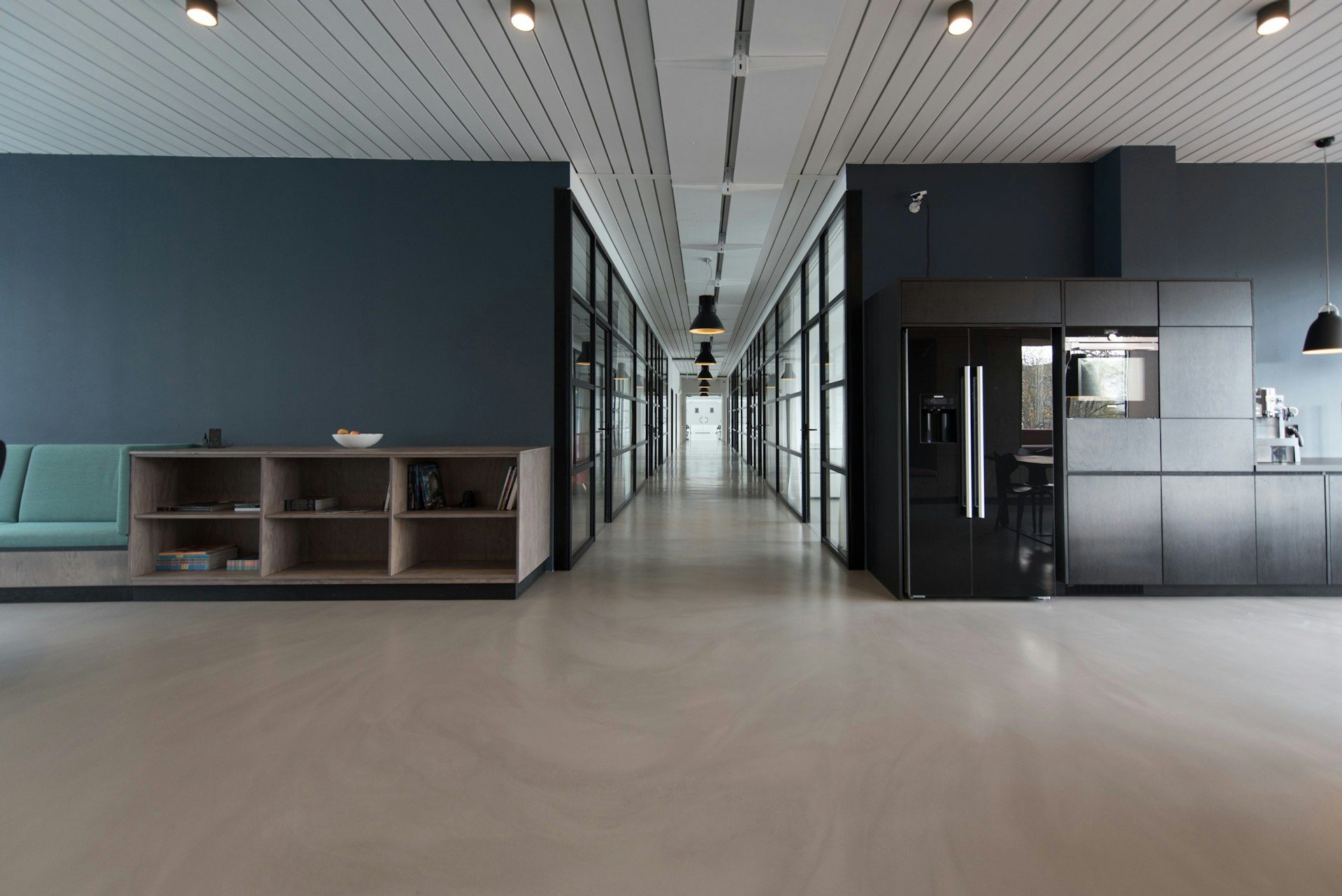 Couloir de bureaux aux cloisons vitrées et coin cuisine dans des locaux d'entreprise