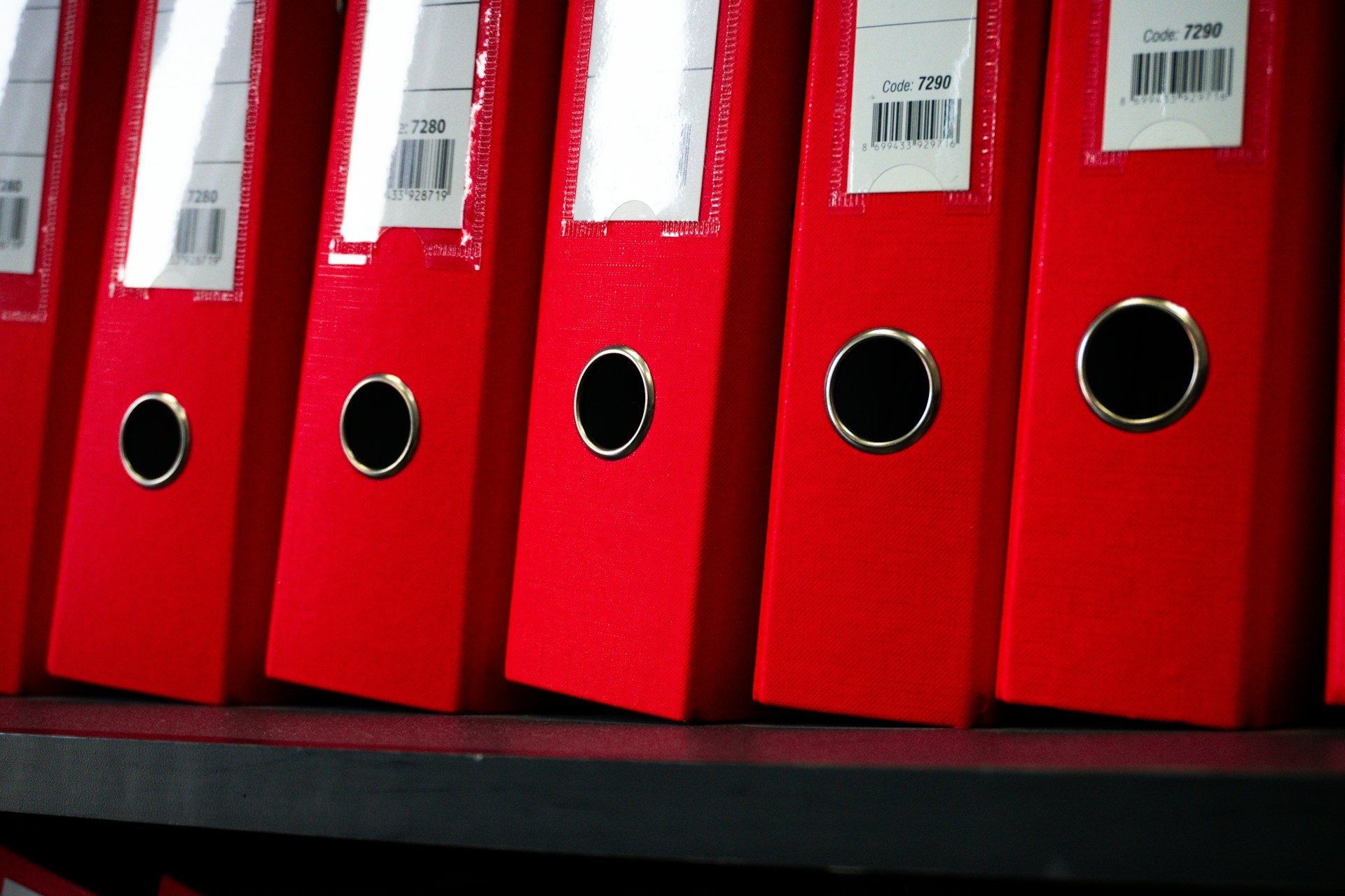Classeurs rouges étiquetés alignés sur une étagère